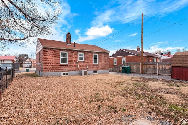 5857 S 2625 W, Roy, UT 84067 - back of house with brick siding, a chimney, a fenced backyard, an outbuilding, and a shed