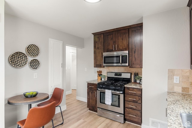 5857 S 2625 W, Roy, UT 84067 - kitchen featuring appliances with stainless steel finishes, decorative backsplash, dark brown cabinetry, light wood-style floors, and light stone counters