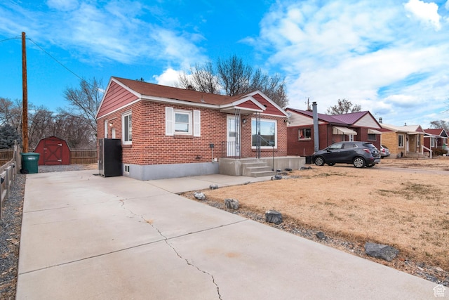 5857 S 2625 W, Roy, UT 84067 - view of front of house with brick siding, a storage shed, concrete driveway, an outbuilding, and fence