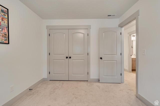 unfurnished bedroom with light colored carpet, baseboards, and a closet