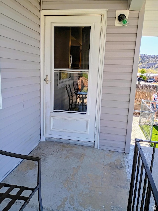 view of exterior entry with fence and a patio
