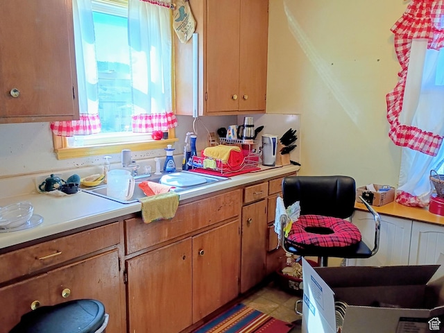 kitchen featuring healthy amount of natural light, light countertops, brown cabinets, and a sink
