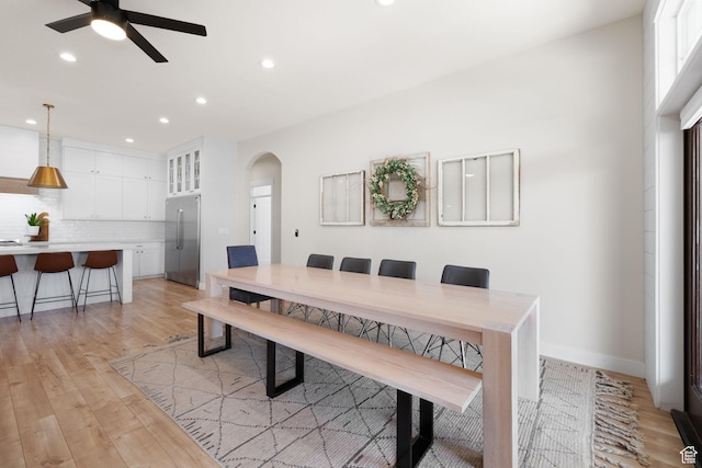 dining space featuring arched walkways, recessed lighting, light wood-type flooring, ceiling fan, and baseboards