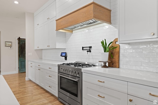 kitchen featuring stainless steel stove, light countertops, custom exhaust hood, white cabinets, and recessed lighting