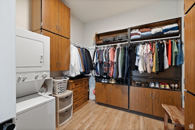 spacious closet featuring stacked washer and clothes dryer and light wood finished floors