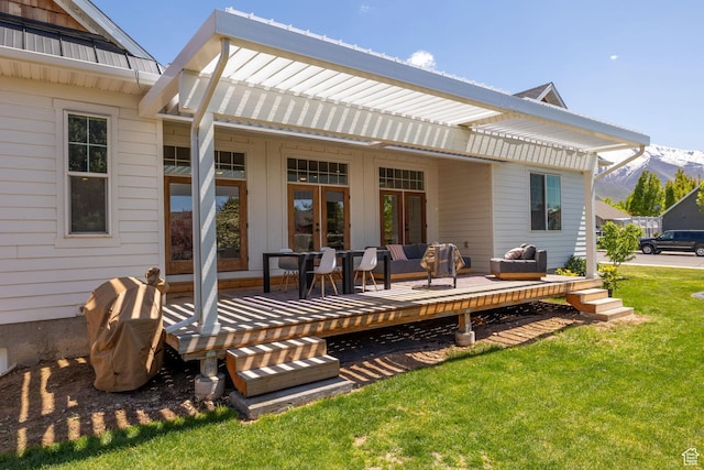 rear view of property featuring a yard, a deck with mountain view, outdoor lounge area, french doors, and metal roof