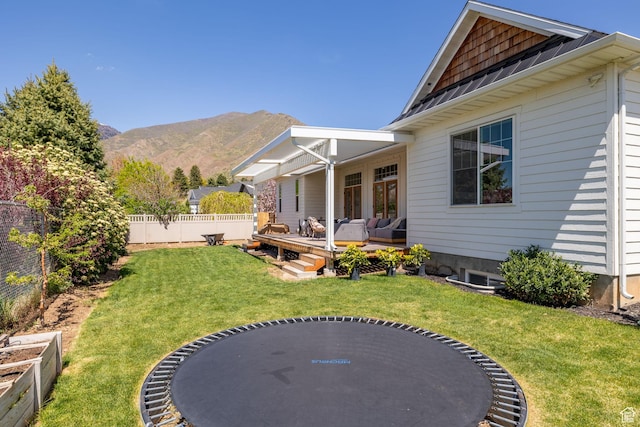 view of yard featuring a deck with mountain view, outdoor lounge area, and a trampoline