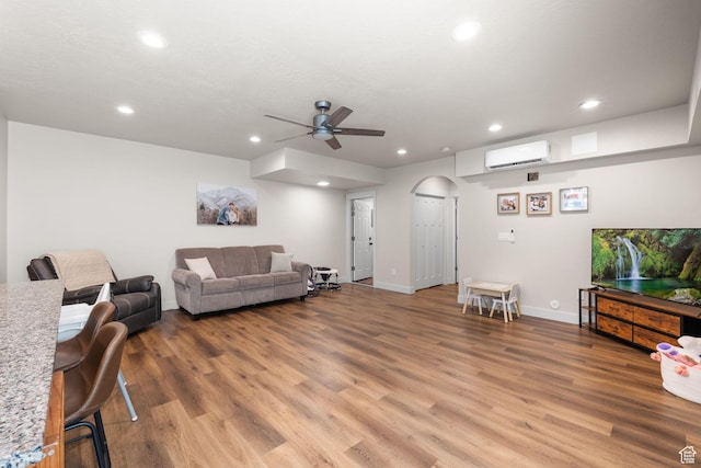 living room with arched walkways, recessed lighting, ceiling fan, light wood-type flooring, and an AC wall unit