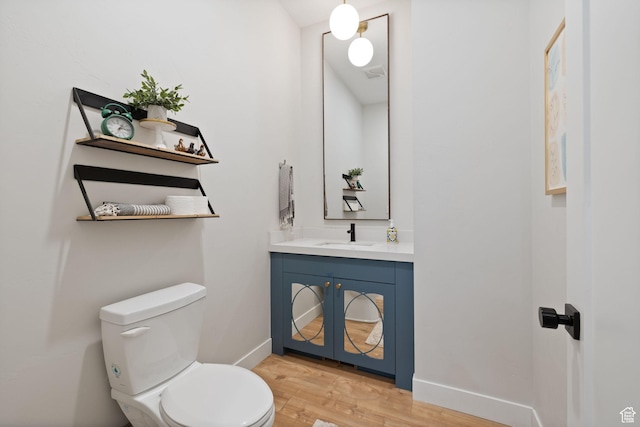 bathroom with wood finished floors, vanity, toilet, and baseboards