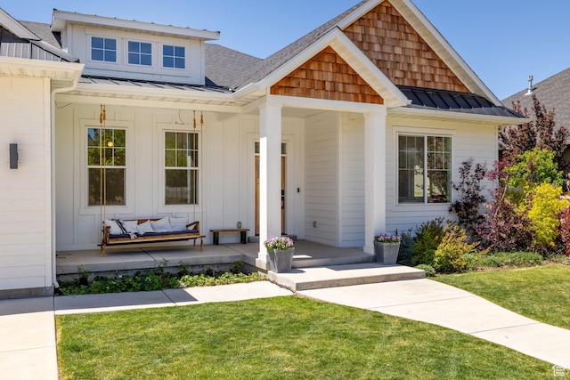 view of front of house featuring a porch, a standing seam roof, a front lawn, and metal roof