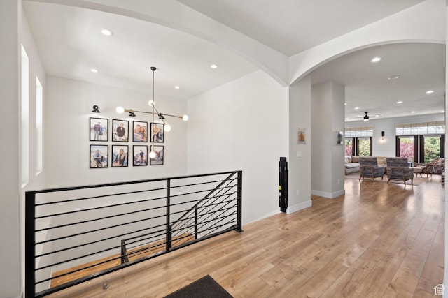 corridor featuring recessed lighting, an upstairs landing, arched walkways, a chandelier, and wood finished floors