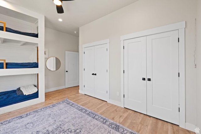 bedroom featuring multiple closets, wood finished floors, baseboards, ceiling fan, and recessed lighting