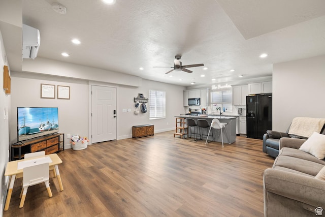 living area with recessed lighting, ceiling fan, wood finished floors, and baseboards