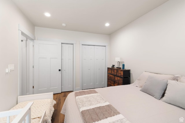 bedroom with wood finished floors, two closets, and recessed lighting