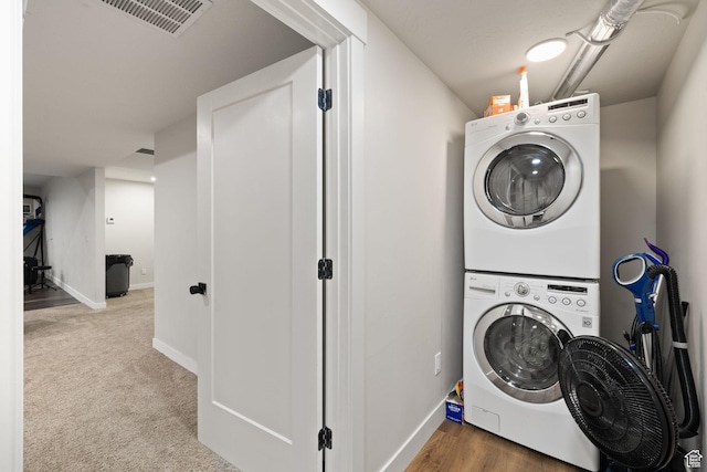 laundry room with stacked washing machine and dryer and baseboards