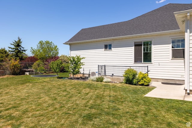 back of property featuring a lawn, a shingled roof, and a patio area
