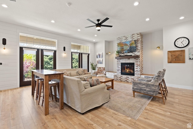 living area featuring light wood-style floors, a ceiling fan, a brick fireplace, recessed lighting, and baseboards