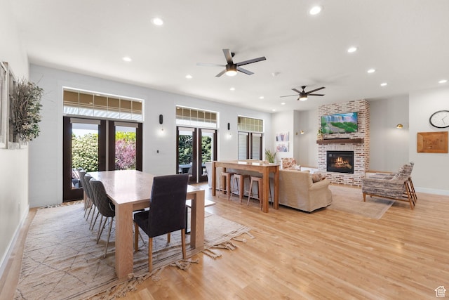 dining space featuring a fireplace, light wood-style flooring, recessed lighting, a ceiling fan, and baseboards