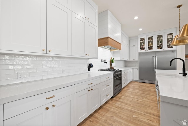 kitchen featuring high quality appliances, custom exhaust hood, backsplash, white cabinetry, and decorative light fixtures