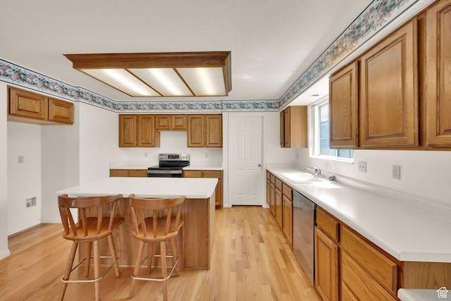 kitchen with stainless steel appliances, brown cabinets, light wood-style flooring, and light countertops