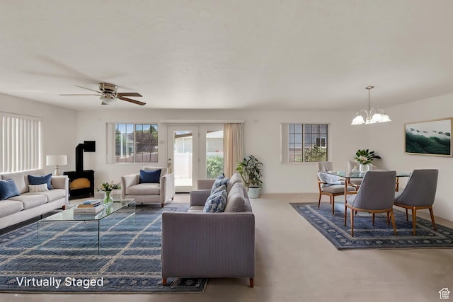 carpeted living area with a wood stove, a chandelier, and ceiling fan