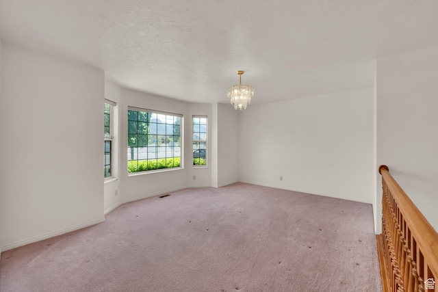 carpeted empty room with a chandelier and baseboards