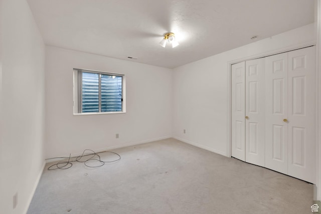 unfurnished bedroom with carpet flooring, baseboards, and a closet