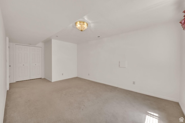 unfurnished bedroom with light colored carpet, a closet, and baseboards