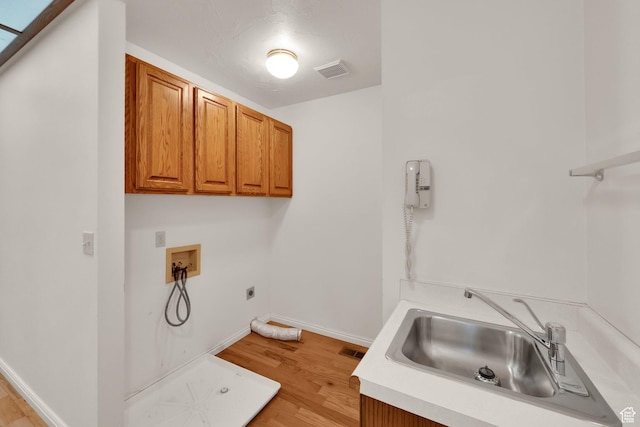 laundry area featuring hookup for an electric dryer, cabinet space, hookup for a washing machine, and light wood-type flooring
