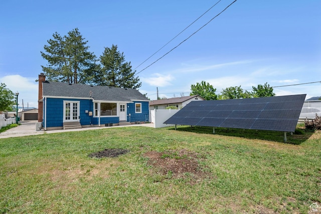 back of property with ground mounted solar panels, a chimney, and entry steps