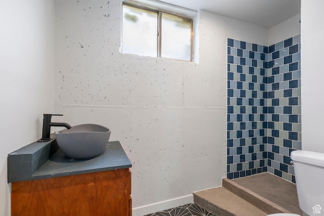 full bathroom featuring toilet, tiled shower, and vanity