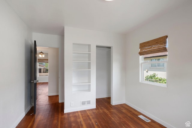 unfurnished bedroom featuring baseboards, dark wood-style flooring, and a closet