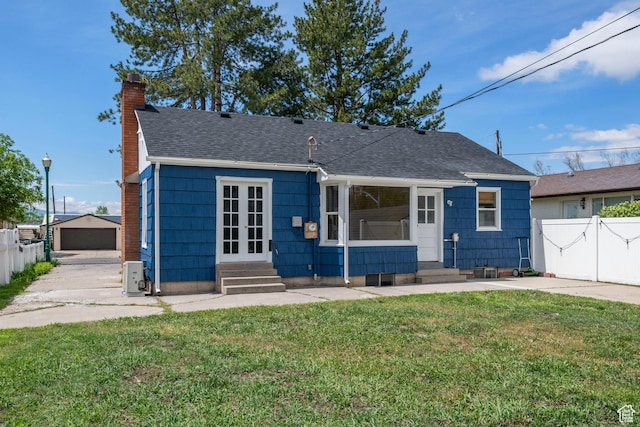 bungalow featuring entry steps, a chimney, a shingled roof, a detached garage, and an outdoor structure
