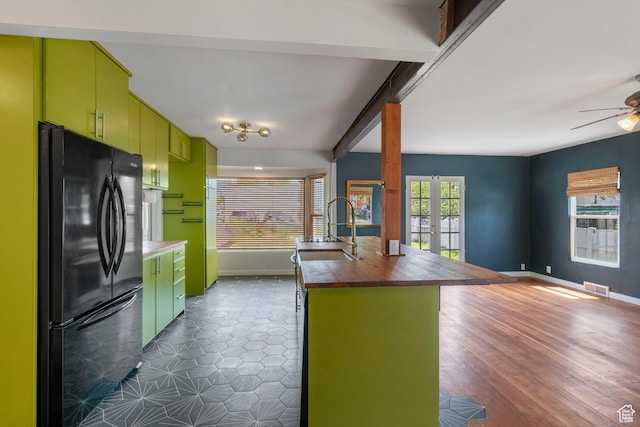 kitchen featuring freestanding refrigerator, a sink, wood counters, baseboards, and ceiling fan