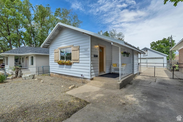 view of front of home featuring fence, an outdoor structure, a detached garage, and roof with shingles