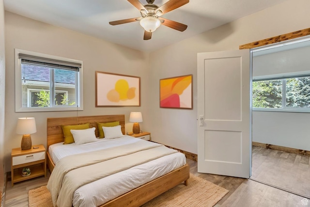 bedroom with light wood-style flooring, baseboards, and a ceiling fan