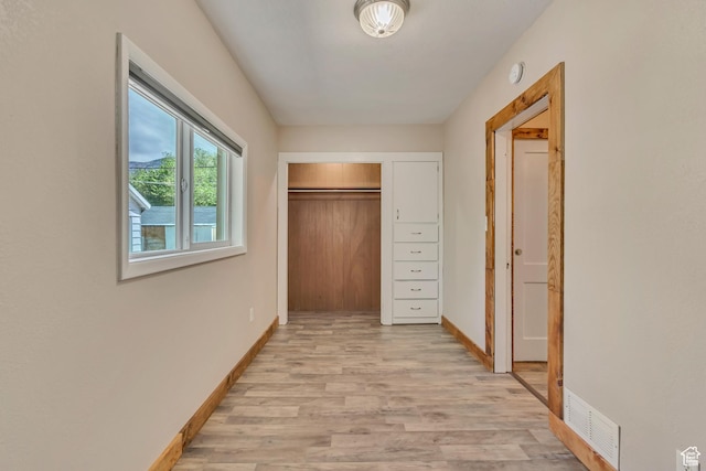 corridor with light wood-style floors and baseboards