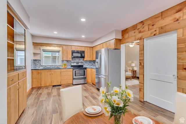 kitchen with stainless steel appliances, a sink, backsplash, light wood finished floors, and recessed lighting