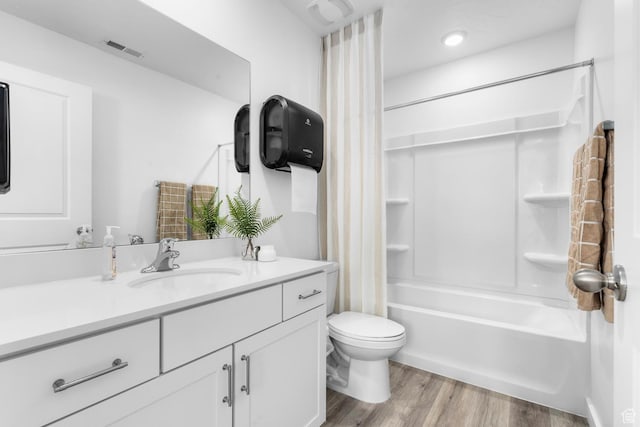 bathroom featuring wood finished floors, toilet, vanity, and shower / bath combo