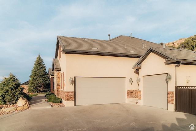1866 N Matchstick Way, Cedar City, UT 84721 - view of side of property featuring stucco siding, driveway, brick siding, and an attached garage