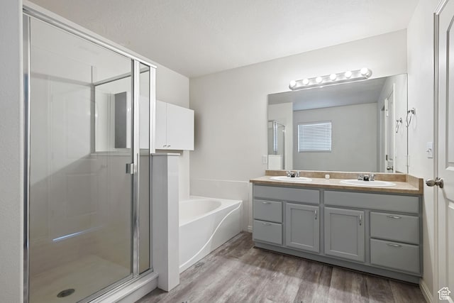 bathroom with a stall shower, wood finished floors, a garden tub, and double vanity
