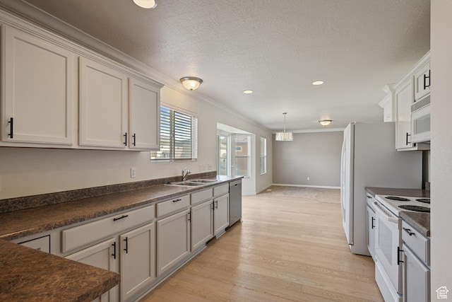 kitchen featuring white appliances, a sink, dark countertops, light wood-type flooring, and crown molding