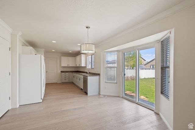 kitchen featuring freestanding refrigerator, crown molding, stainless steel dishwasher, light wood-style floors, and dark countertops