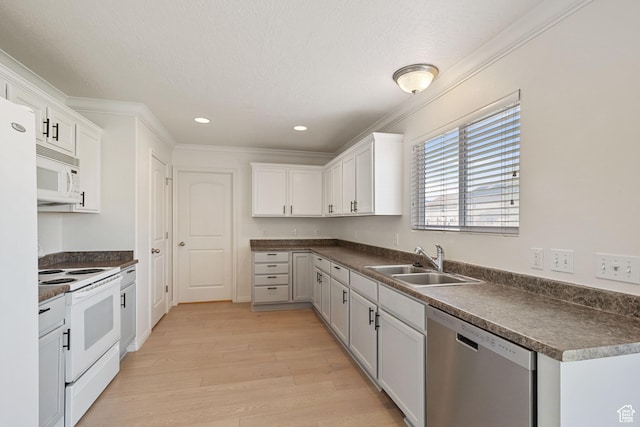 kitchen featuring white appliances, a sink, light wood finished floors, dark countertops, and crown molding
