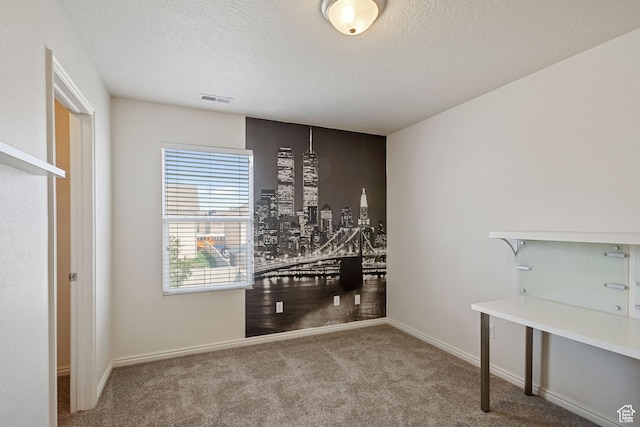 carpeted empty room with a textured ceiling and baseboards