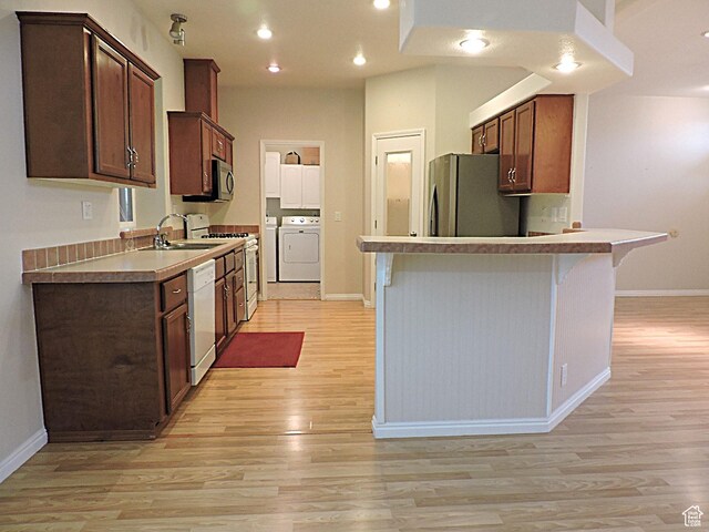 681 E Sunset St, Delta, UT 84624 - kitchen featuring white appliances, washing machine and dryer, a sink, light wood-style flooring, and baseboards