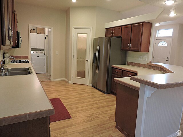 681 E Sunset St, Delta, UT 84624 - kitchen featuring a sink, washer / clothes dryer, light wood-type flooring, stainless steel fridge with ice dispenser, and a kitchen bar
