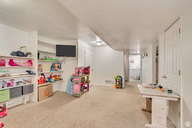 recreation room featuring carpet, a textured ceiling, and baseboards