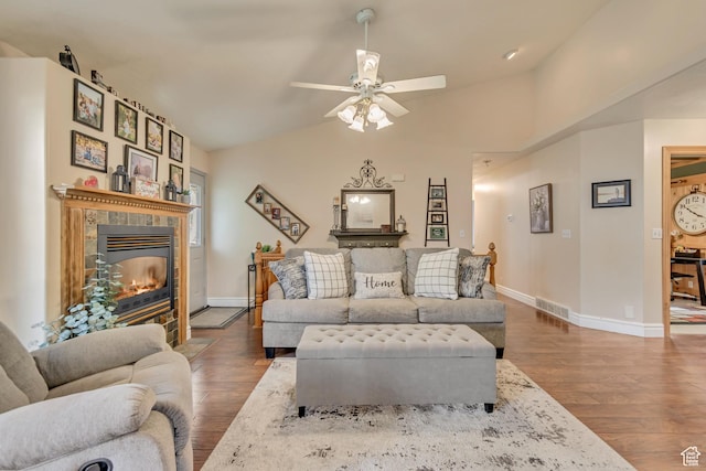 living area with wood finished floors, a tile fireplace, baseboards, ceiling fan, and lofted ceiling