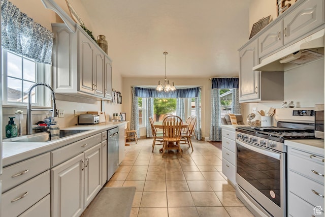 kitchen with appliances with stainless steel finishes, under cabinet range hood, a chandelier, a sink, and light countertops